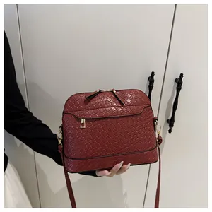 Close-up of wine red shell bag showing detailed woven leather texture and gold zipper