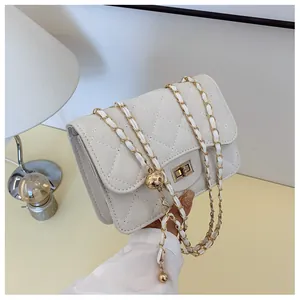Detail of cream quilted handbag featuring a gold metal ball and turn-lock closure