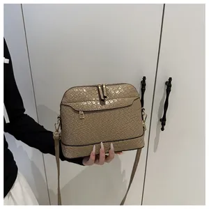 Close-up of khaki woven texture PU leather shell bag with gold zippers and long strap