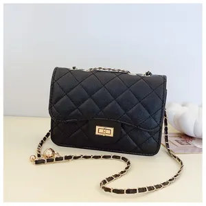 Detailed view of black quilted faux leather crossbody bag with golden chain and ball charm