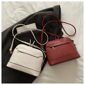 Detail of woven texture seashell bags in white and burgundy with gold hardware