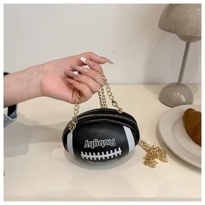 Detail of rugby-shaped black leather bag with white stitching and gold chain strap