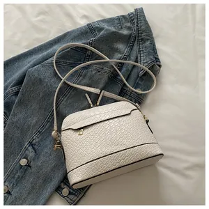 Close-up of white woven texture shell bag with gold hardware on denim jacket