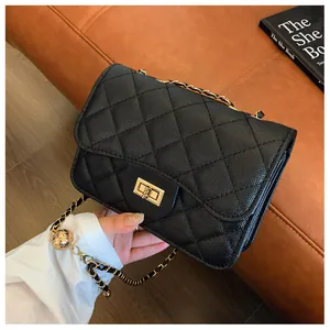 Detail of black quilted leather crossbody bag with golden chain and ball charm