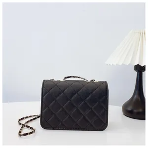 Detailed view of black quilted chain bag with elegant metal lock and leather strap