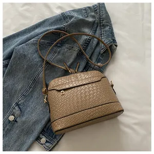 Top view of light brown woven texture shell bag with gold hardware on denim background