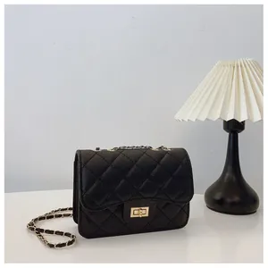 Detail of black quilted leather shoulder bag featuring a golden clasp and chain strap