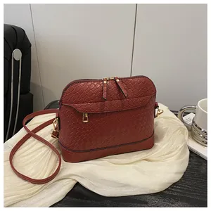 Close-up of dark red woven texture on a shell bag with golden metal zipper and hardware