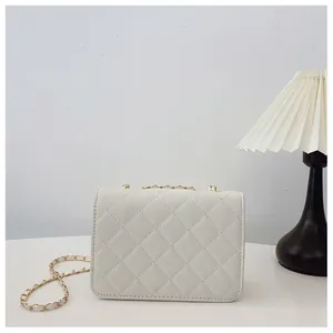 Detail shot of white quilted shoulder bag with gold chain and woven leather strap