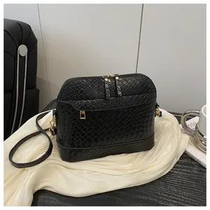 Close-up of black shell handbag with python texture and elegant gold zipper details