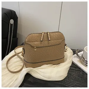 Detail of light brown shell bag featuring woven texture leather and gold metal zippers