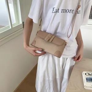 Détail de la texture tissée beige et des finitions en cuir camel sur un sac porté croisé