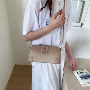 Détail du sac bandoulière tressé beige et marron porté par un mannequin pour la taille