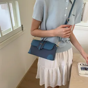 Détail du sac tressé bleu contrasté avec bandoulière en cuir réglable et boucle dorée