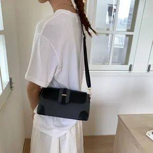 Détail du sac bandoulière tissé gris avec bordure en cuir noir et fermoir doré sur le modèle