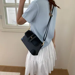 Détail du sac bandoulière noir avec texture tissée, rabat en cuir et boucle dorée