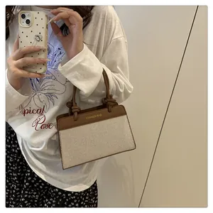 Detail of canvas square bag with brown leather knot handle and front fashion text