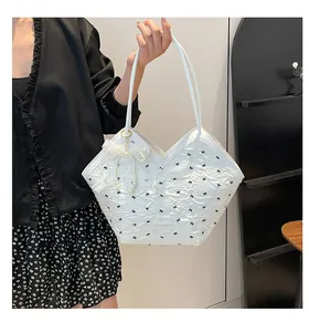 Close-up of white bucket bag with black bow patterns and a pearl lace pendant charm