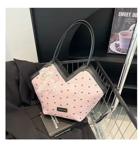 Detail of light pink tote bag with black bow pattern and lace pearl pendant in a shopping cart