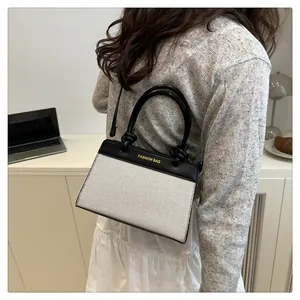 Detail of contrast stitching, gold logo, and unique knotted handle on the square handbag