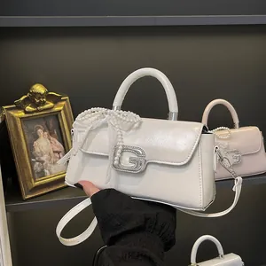 Detail of cream leather handbag with crystal G buckle and pearl lace ribbon decor