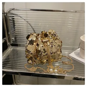 Dettaglio borsa a secchiello con paillettes dorate catena metallica e perle bianche