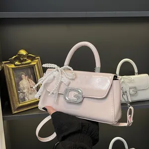 Detail of light pink glossy handbag with crystal G-buckle and elegant lace pearl bow
