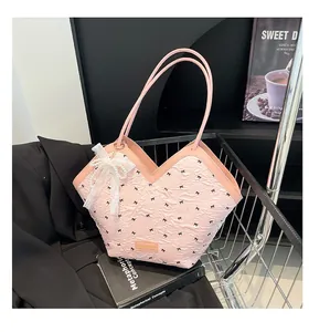 Detail view of pink puff-textured tote bag with black bows and pearl lace pendant