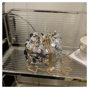 Dettaglio borsa a secchiello con paillettes argento catena dorata e ciondoli con perle