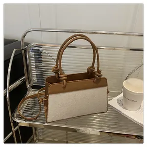 Detail of color-block tote bag with brown leather handles and knot accents on a cart
