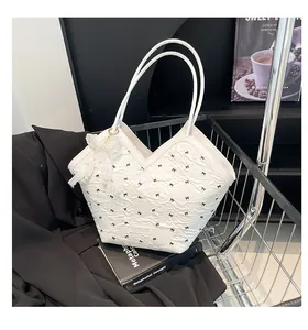 Close-up of white bucket bag with black bow embroidery and pearl lace charm detail