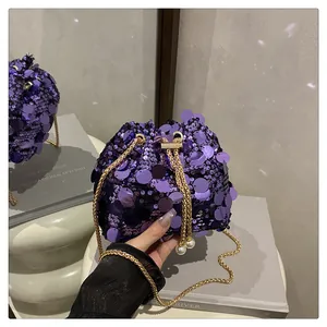 Dettaglio della borsa a secchiello con paillettes viola, catena d'oro e grandi perle