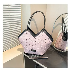 Detail of pink pleated bucket bag with black bow print and fashion label on a book