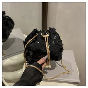 Dettaglio della borsa a secchiello con paillettes nere, catena dorata e perle