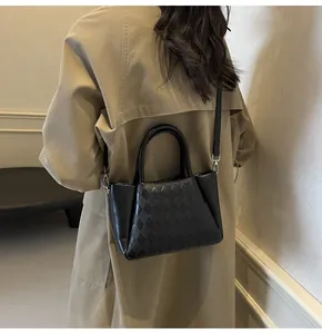 Detailansicht der schwarzen gewebten Handtasche, getragen von einem Modell im Trenchcoat