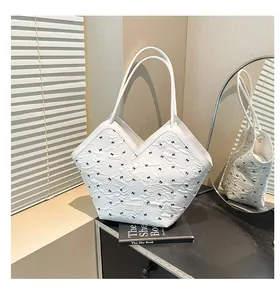 Detail of white pleated bucket bag with black bow embroidery and metal brand logo plate