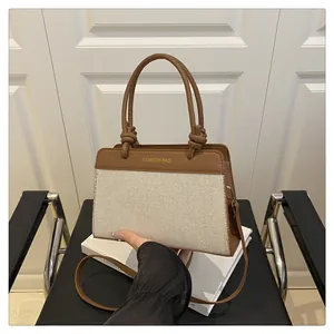 Detail of canvas tote bag with brown leather trim and FASHION BAG text embroidery