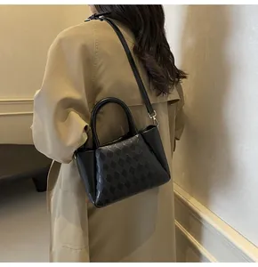 Detail einer schwarzen gesteppten Beuteltasche, über der Schulter mit Trenchcoat getragen