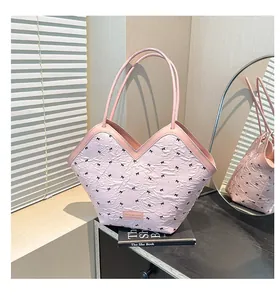 Pink bucket bag with black bow patterns and V-cut opening detail on a book