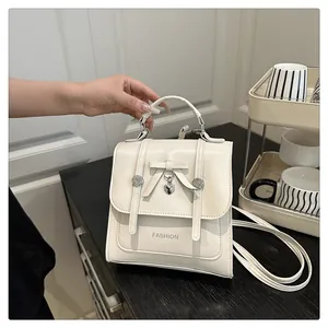 Detail of cream mini backpack featuring a metallic heart pendant and bow decoration