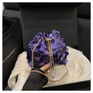 Dettaglio borsa a secchiello con paillettes viola, catena dorata ed eleganti lacci di perle