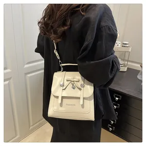 Detail of off-white mini bag featuring a decorative bow, heart pendant and fashion text