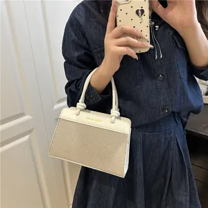 Elegant beige canvas handbag with white leather trim and gold fashion bag lettering