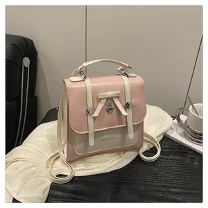 Detailed view of pink and beige crossbody bag with bow charm on a velvet prop