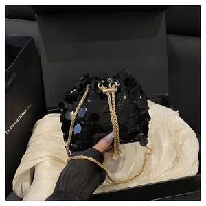 Dettaglio della borsa a secchiello con paillettes nere, catena dorata e ciondoli di perle