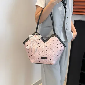 Pink tote bag with pleated texture, black bow patterns, and lace pearl charm accessory
