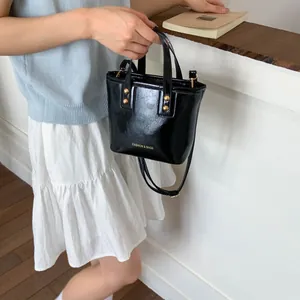 Detail of black glossy bucket bag with gold studs and FASHION & BAGS lettering text