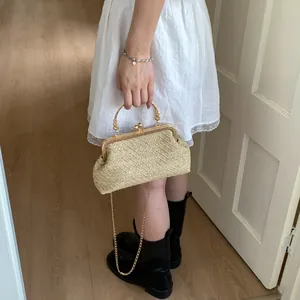 Detail of woven straw handbag featuring vintage metal frame and gold ring handle