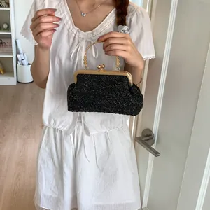 Detailed macro of vintage black woven handbag with gold metal frame and floral handle carvings