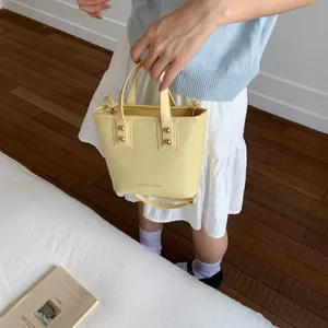 Close-up of light yellow leather bucket bag with top handle and Fashion & Bags lettering